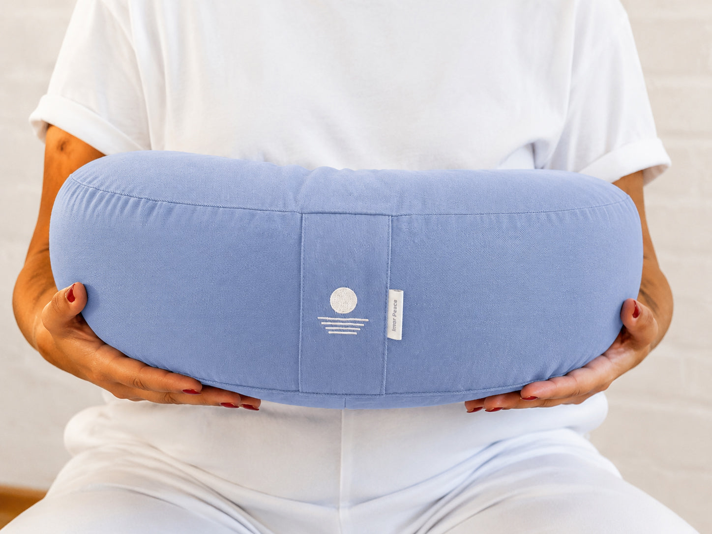 Person hält Halbmond-Meditationskissen in Hellblau – Yoga Kissen halbrund aus Baumwolle