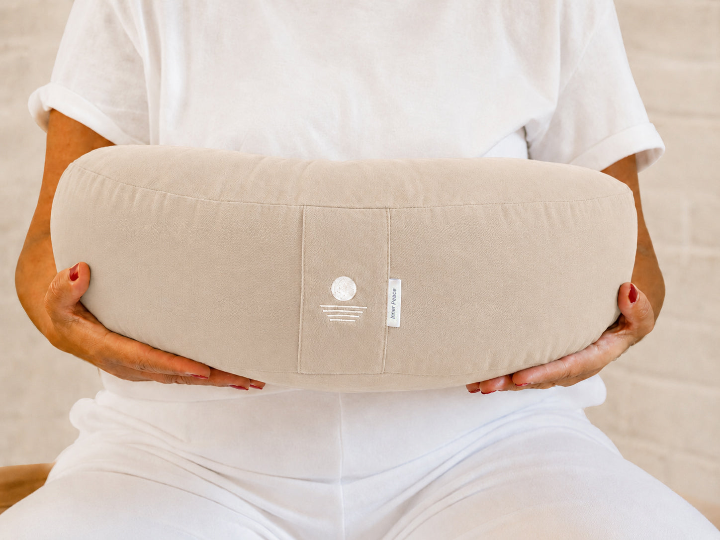 Person hält Halbmond-Meditationskissen in Light Taupe – Yoga Kissen halbrund aus Baumwolle